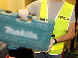 Na zdjęciu policjant w kamizelce z napisem &quot;Policja&quot; trzyma skrzynkę z elektronarzędziami.