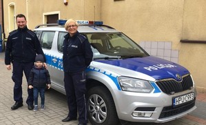 policjanta, policjantka i dziecko stoją na tle radiowozu
