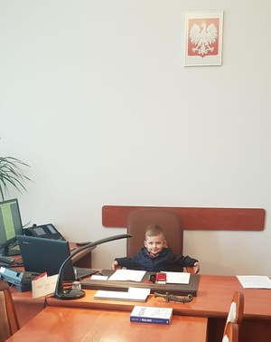 mały chłopiec wystaje za biurka komendanta powiatowego
