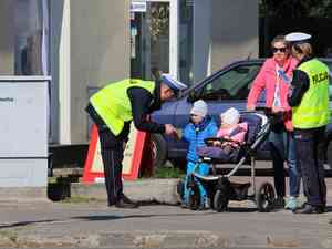 policjant daje odblaks dziecku siedzaemu w wozku