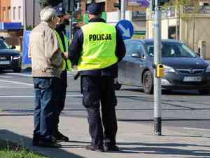 policjant rozmawia z seniorem stojac przy przejsciu dla pieszych