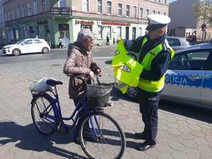 policjant daje kamizelke odblaskowa rowerzyscie