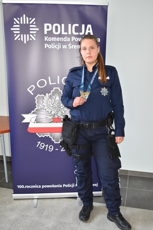 Umundurowana policjantka stoi i trzyma w ręce medal