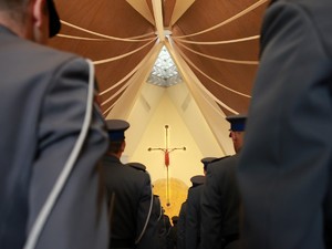 Kompania honorowa stoi w kościele w dwuszeregu. Przed nimi w tle krzyż. Zdjęcie zrobione od tyłu.