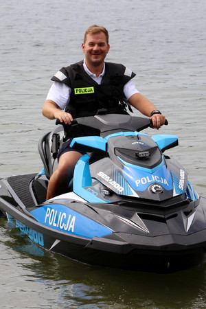 Sierżant sztabowy Patryk Chrastek z Komisariatu Wodnego Policji w Poznaniu siedzi na skuterze wodnym policyjnym.