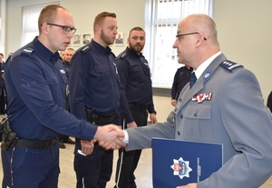 Komendant śremskiej policji w galowym mundurze gratuluje umundurowanego policjantowi