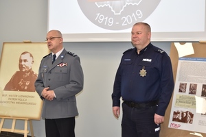 Komendant w galowym mundurze mówi do policjantów, obok niego stoi policjant w mundurze