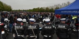 Czterej policjanci służby ruchu drogowego stoją na tle zlotu motocyklowego