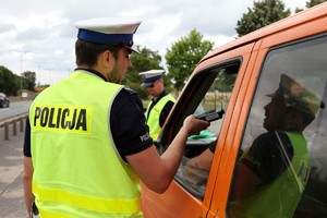 Policjant ruchu drogowego sprawdza alkomatem stan trzeźwości kierowcy.