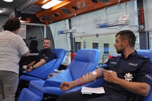 policjanci oddają krew siedząc na fotelach w krwiobusie