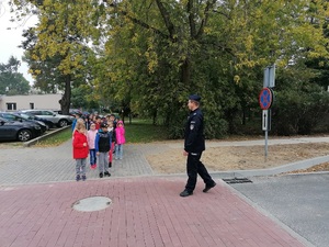 Policjant w mundurze rozmawia z dziećmi na ulicy o bezpieczeństwie na drodze