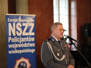 przewodniczący związku zawodowego policjantów przemawia na tle baneru