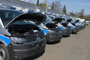 Nowoczesne furgony patrolowe VW T6 dla policjantów z całej Polski stoją na parkingu z otwartymi maskami