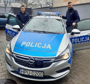 Zdjęcie archiwalne dzielnicowych z poznańskiej Wildy - przy oznakowanym radiowozie stoi dwóch umundurowanych policjantów.