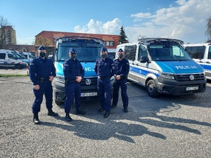 Policjanci z Oddziału Prewencji Policji w Poznaniu, którzy uratowali 16-miesięczną dziewczynkę, na tle oznakowanego radiowozu.