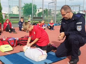 Ratownik medyczny w policyjnym mundurze uczy pierwszej pomocy uczestników sportowej kolinii