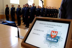 Zdjęcie sali, gdzie w tle widać ślubujących policjantów