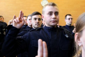 Zdjęcie sali, gdzie w tle widać ślubujących policjantów