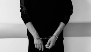 czarno- białe zdjęcie mężczyzny z rękoma skutymi kajdankami