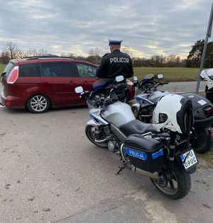 policjant przy motocyklu i samochodzie