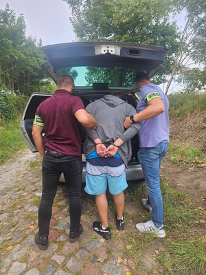 policjanci z zatrzymanym, narzędzia w bagażniku