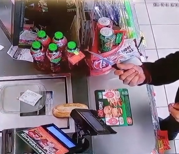 policjanci z zatrzymanym; ręka trzymająca nóż nad ladą sklepową