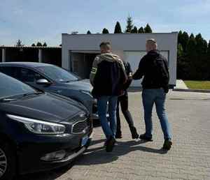 policjanci z zatrzymanymi przy samochodzie