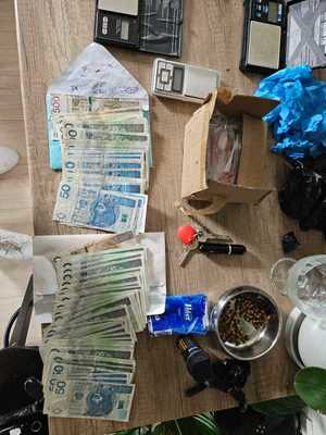 policjanci z zatrzymanym; zabezpieczone narkotyki, papierosy i pieniądze