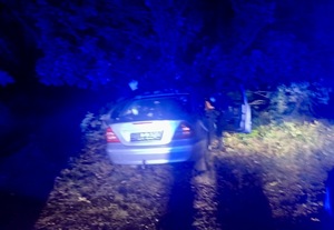 rozbite białe auto; policjant i strażacy wyciągający mężczyznę z samochodu