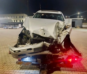rozbite białe auto; policjant i strażacy wyciągający mężczyznę z samochodu