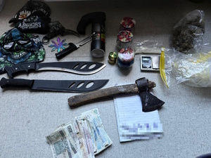 policjant z zatrzymanym; zabezpieczone przedmioty - pieniądze, narkotyki, maczety, siekiera, maski, gaz