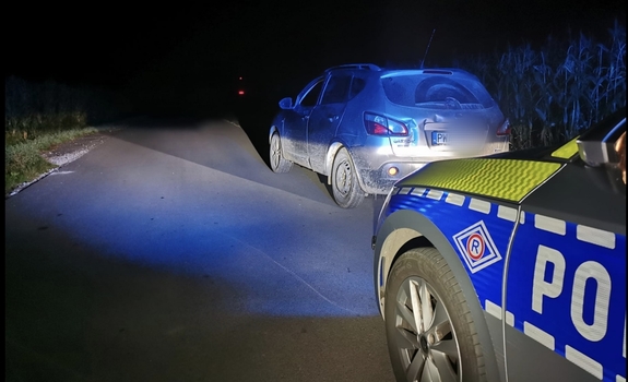 noc, samochód stoi na poboczu obok pola kukurydzy, za nim radiowóz