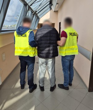 policjanci prowadzą zatrzymanych; zabezpieczone przedmioty; odzyskane auta