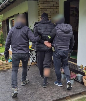 policjanci prowadzą zatrzymanych; zabezpieczone przedmioty; odzyskane auta