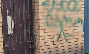 policjanci z zatrzymanym; pomalowane sprayem ściany budynków
