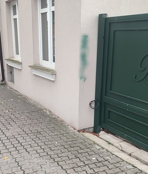 policjanci z zatrzymanym; pomalowane sprayem ściany budynków