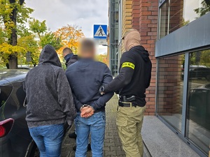 policjanci z zatrzymanymi; plik zabezpieczonych pieniędzy