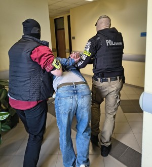 policjanci z zatrzymanymi; plik zabezpieczonych pieniędzy