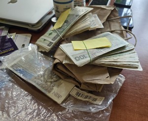 policjanci z zatrzymanymi; plik zabezpieczonych pieniędzy