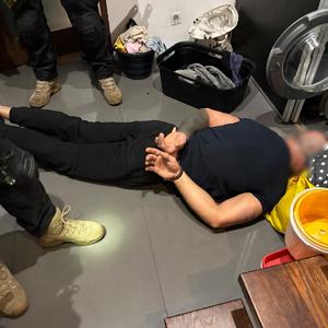 Mężczyzna zatrzymany przez policjantów leżący na podłodze, w kajdankach