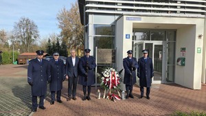 Policjanci podczas składania wieńca pod pamiątkową tablicą przed Osiedlowym Domu Kultury w Biedrusku