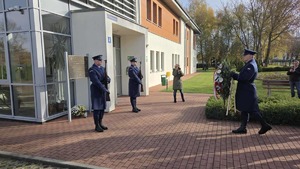 Policjanci podczas składania wieńca pod pamiątkową tablicą przed Osiedlowym Domu Kultury w Biedrusku
