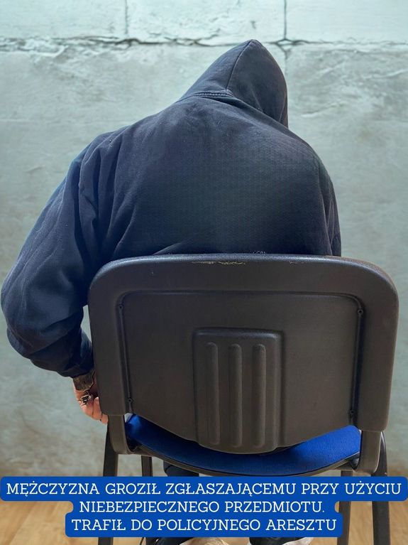 mężczyzna siedzi na krześle z rękoma skutymi kajdankami