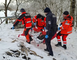 policjant wraz z ratownikami medycznymi przenoszą mężczyznę do karetki