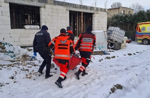 policjant wraz z ratownikami medycznymi przenoszą mężczyznę do karetki