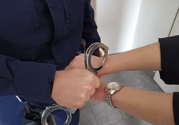policjant zakuwa kobietę w kajdanki
