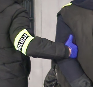 ręka policjanta trzyma ramię zatrzymanego