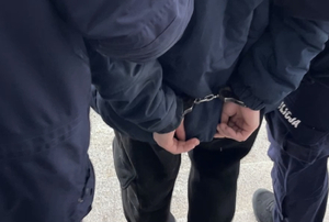 policjanci i mężczyzna z rękoma z tyłu skutymi kajdankami