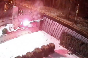 chłopak odpala racę przy ogrodzeniu domu