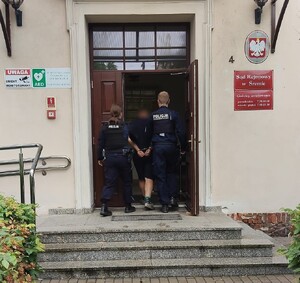 policjanci z zatrzymanym wchodzą do budynku sądu